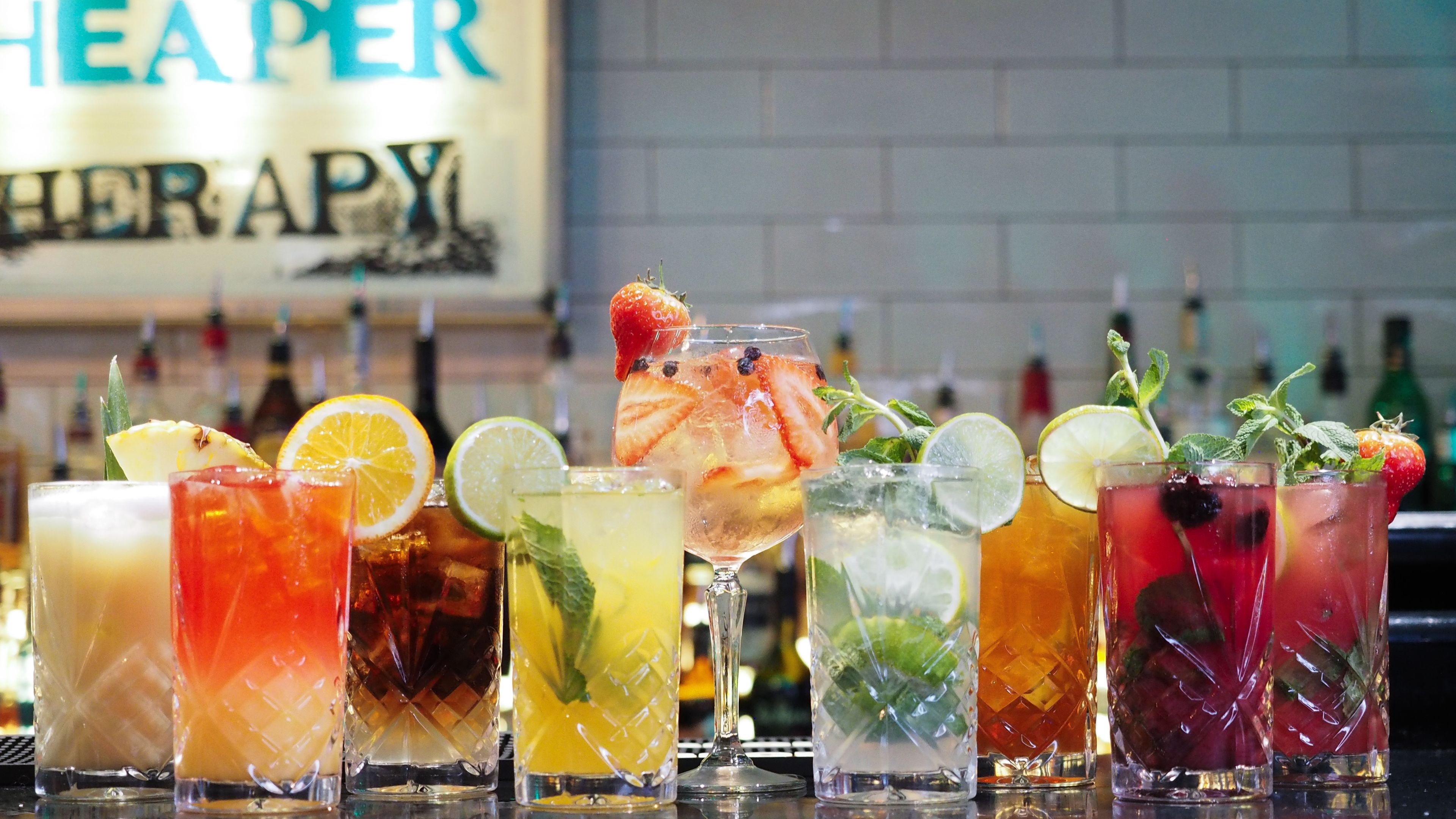 A bar with various drinks, each garnished with fruits and mint leaves.