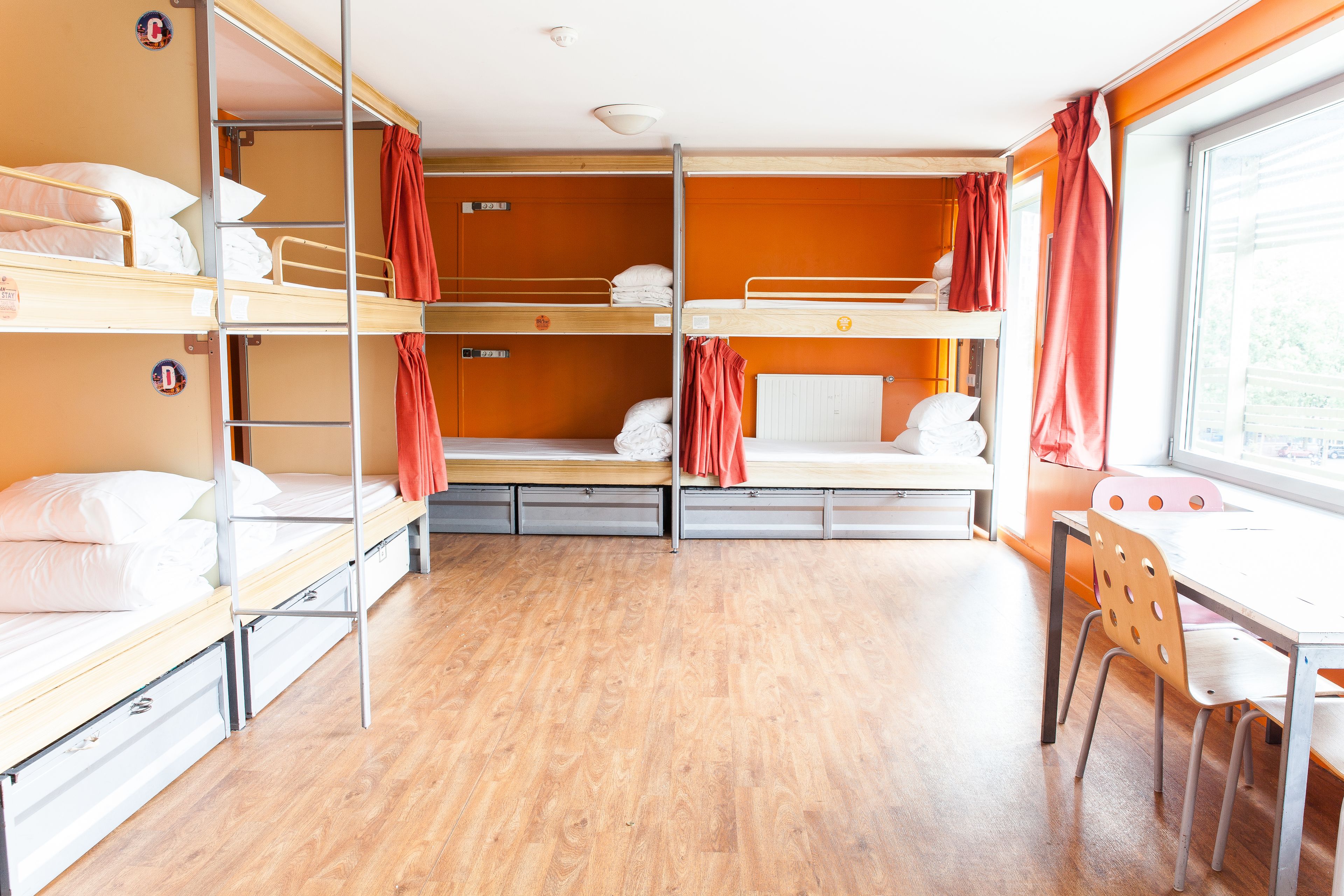 A bunk room with three levels of beds, a desk, and a chair.