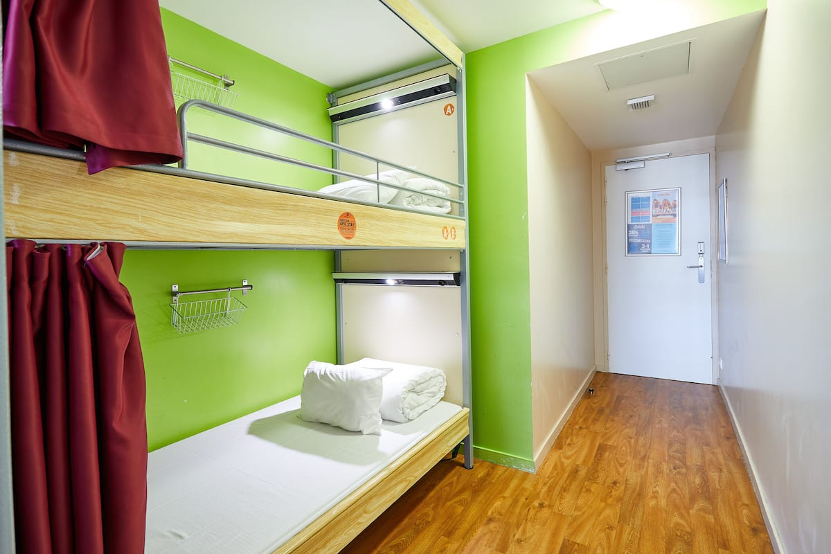 Dormitorio con literas, pared verde, puerta blanca y suelo de madera.