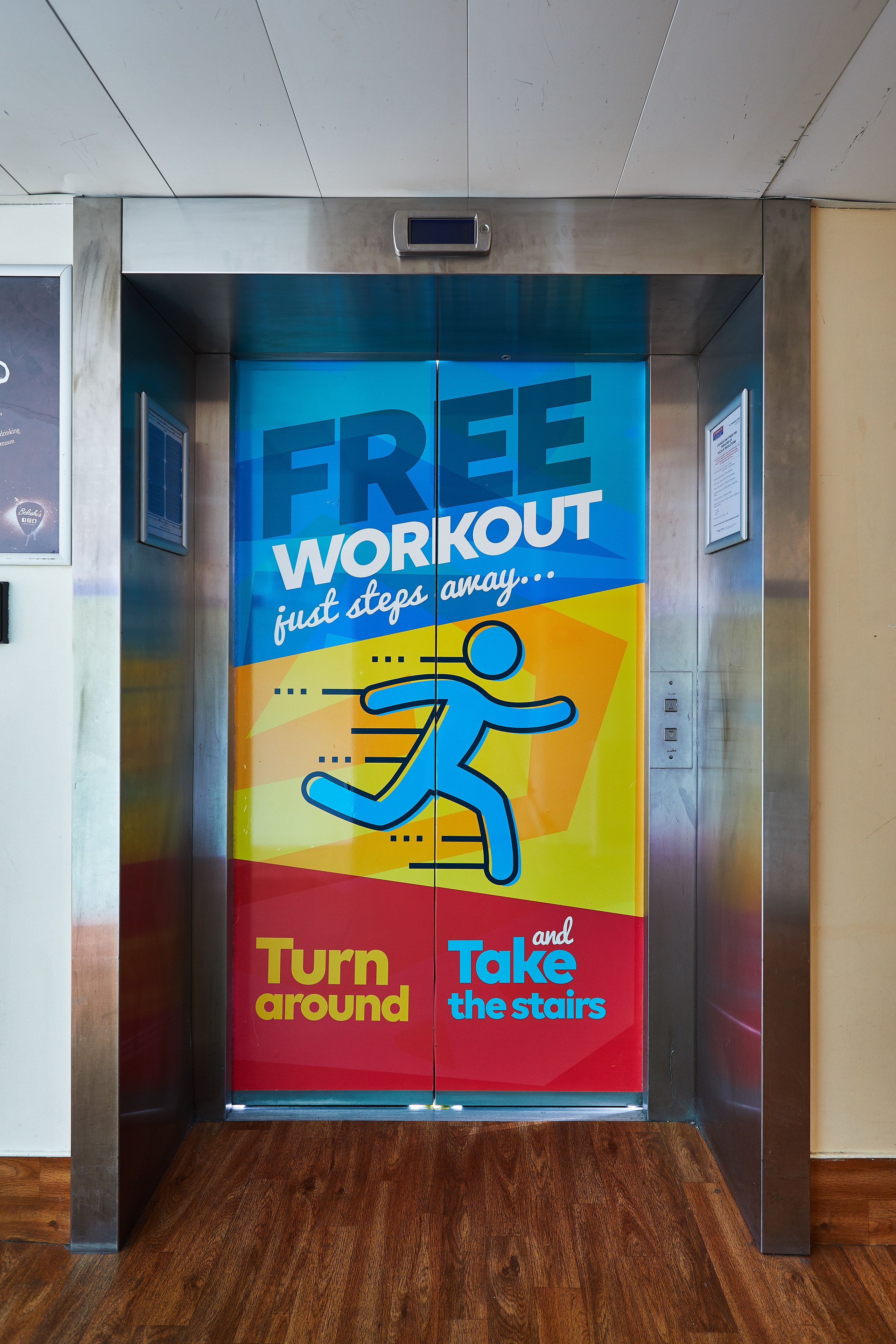 An elevator with a colorful advertisement for a free workout, encouraging people to turn around and take the stairs.