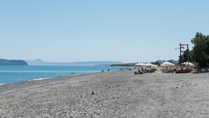 A pebble beach with umbrellas and a lifeguard tower. - Daphnis Villas (Platanias)