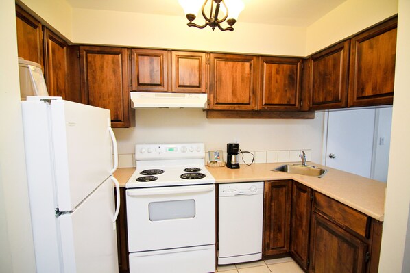 Una cocina con gabinetes de madera, un refrigerador blanco, una estufa y un lavavajillas.