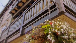 Un edificio de varios pisos con un balcón y una maceta colgante.