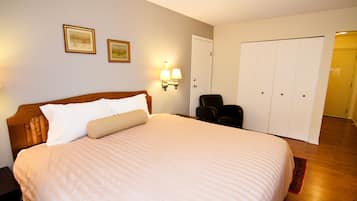 A hotel room with a large bed, a nightstand, a chair, a wardrobe, and two wall-mounted lamps.