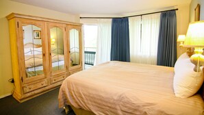 Un dormitorio con una cama grande, un armario de madera y un balcón con cortinas.