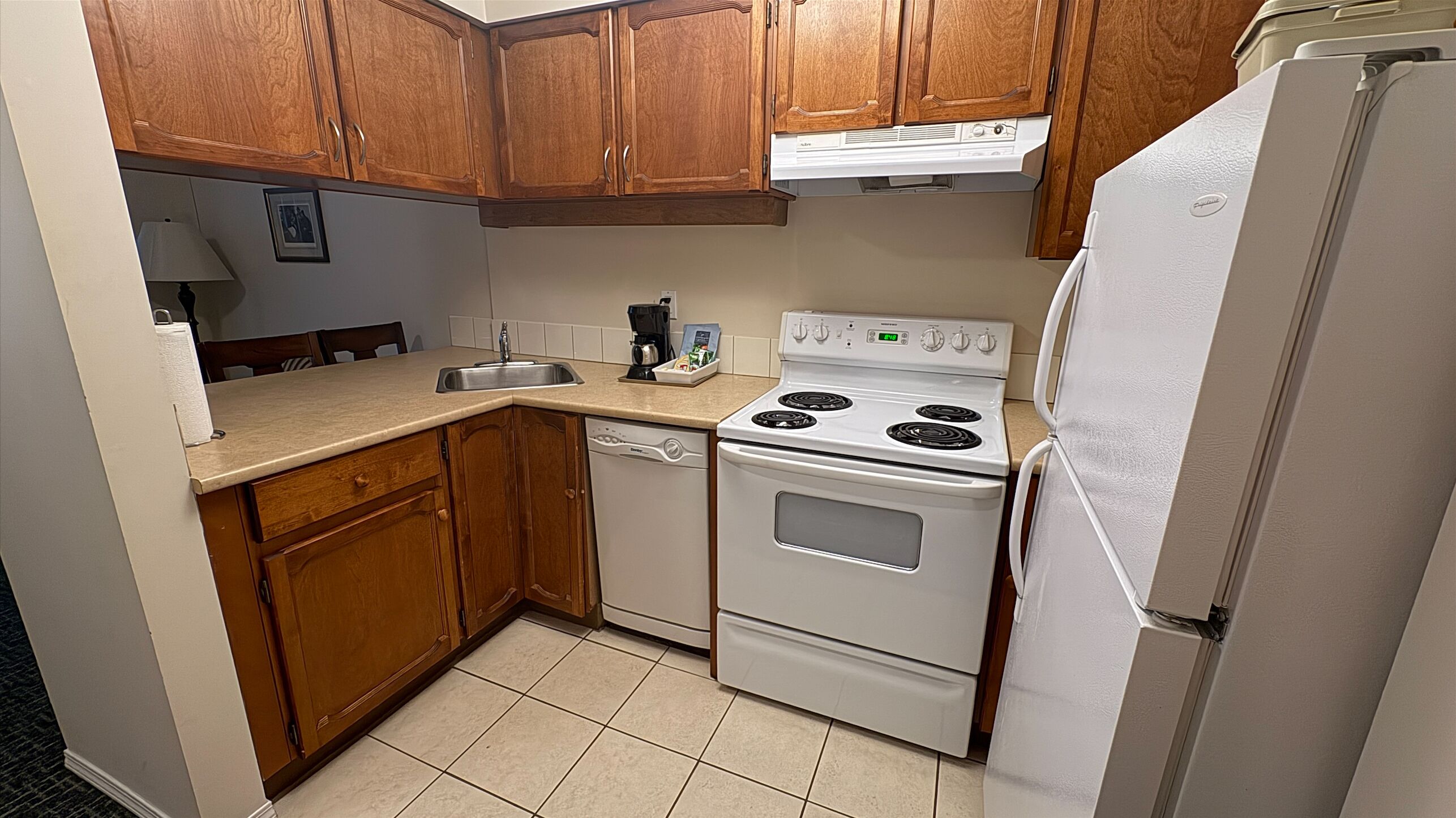 Una cocina compacta con armarios de madera, una estufa blanca y un refrigerador.