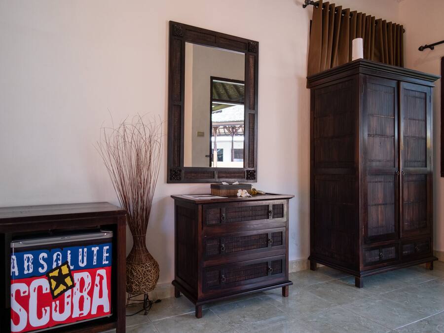 A room with a dark wooden cabinet, a mirror on the wall, and a decorative vase.