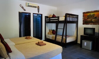 Una habitación de hotel con dos camas, televisión y un mueble pequeño.