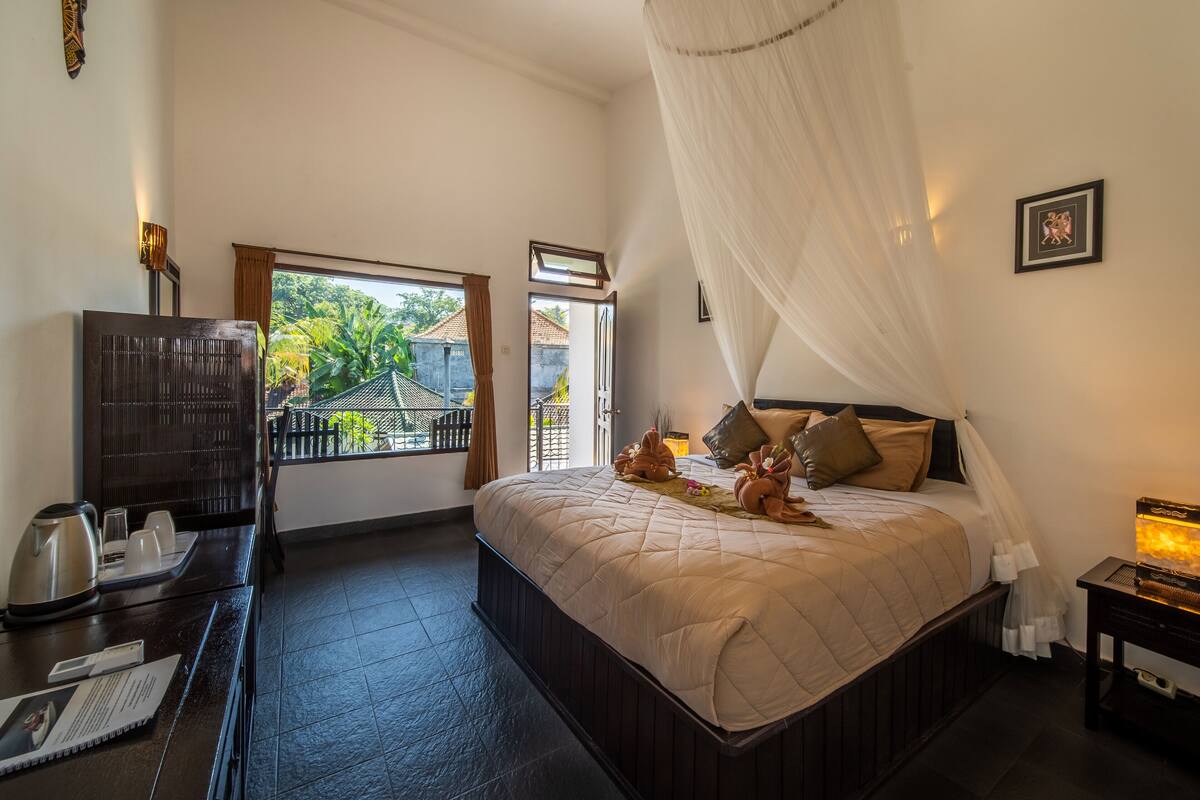 A bedroom with a bed, bedside table, and a view of the outside.