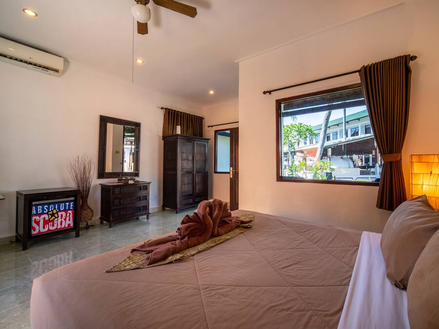 Habitación de hotel con una cama grande, un armario, una tocador con espejo y una ventana con cortinas.