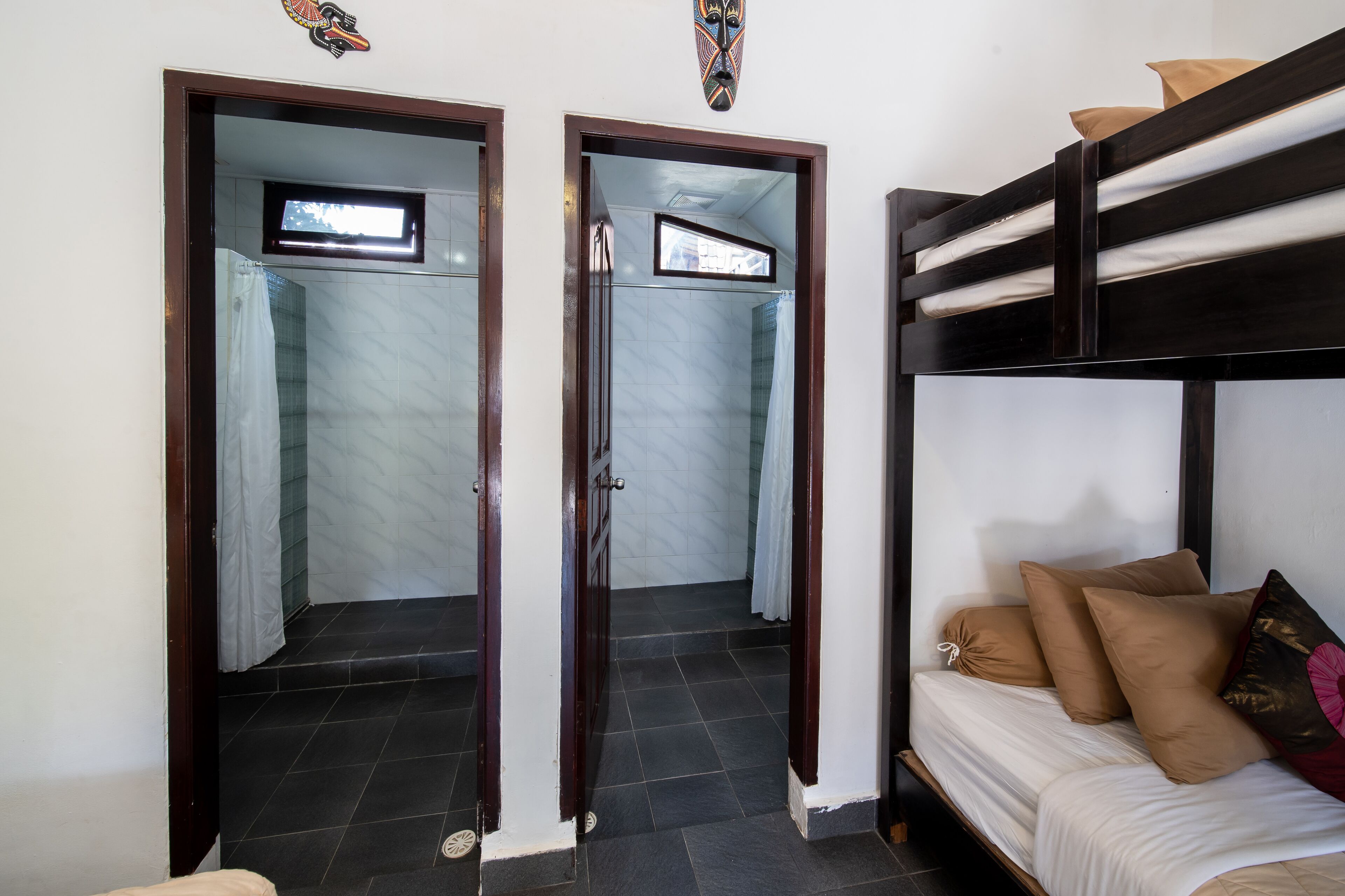 A room with a bunk bed, a small window, and a door leading to a bathroom.