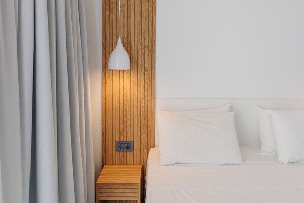 A hotel room with a wooden headboard, a bedside table, and a white lamp.