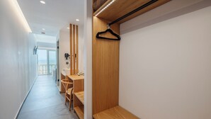 Un pasillo moderno de hotel con un banco de madera, un secador de pelo y un perchero negro colgado.