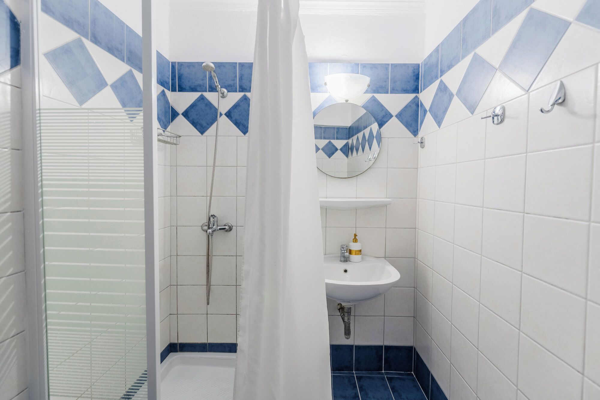 A bathroom with a shower, a sink, and a mirror.