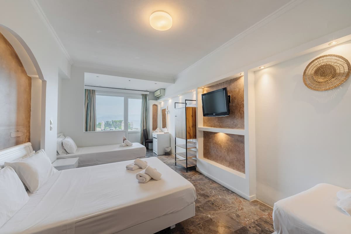 Habitación de hotel con una cama grande, un televisor montado en la pared y vistas de la ciudad.