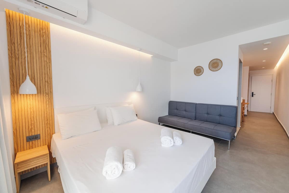 Una habitación de hotel moderna con una cama grande, un sofá gris y una pared de acento de madera.