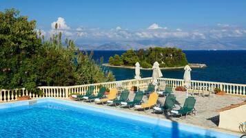Una piscina al aire libre, sombrillas, sillones reclinables de piscina