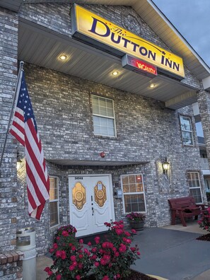 The Dutton Inn with a brick facade, a prominent sign, and a flag. - Dutton Inn (Branson)