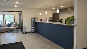 A reception area with a 'WELCOME' sign, a reception desk, a sofa, a coffee table, and potted plants.