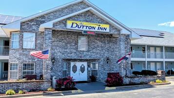 A Dutton Inn building with a stone facade, a signboard, and two American flags.