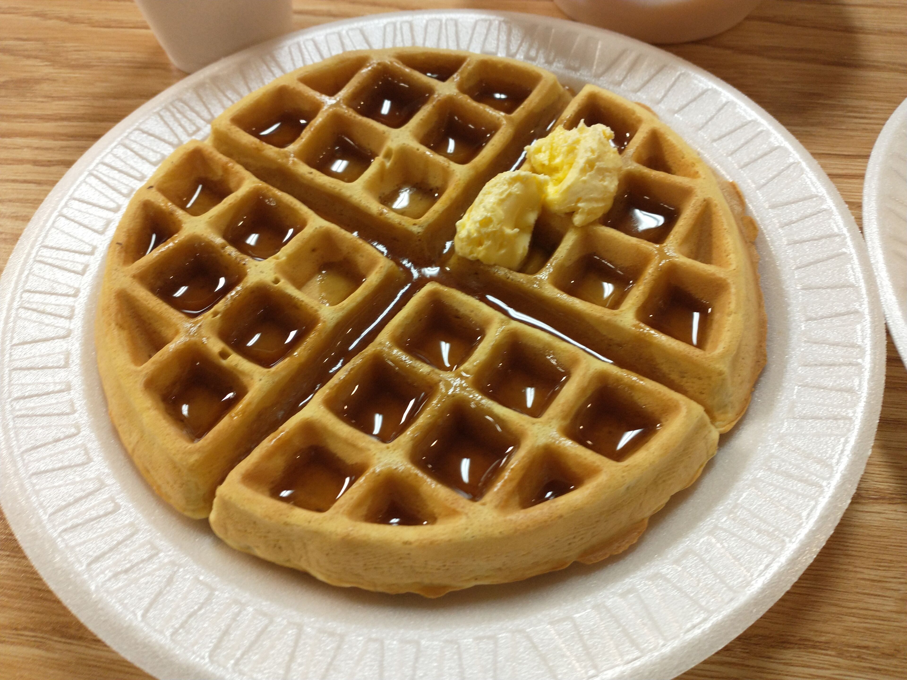 Ein Waffel mit Sirup und Butter auf einem weißen Teller.