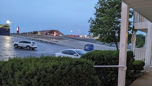 A parking lot with two cars, a building with a red roof, and a blue structure in the background.