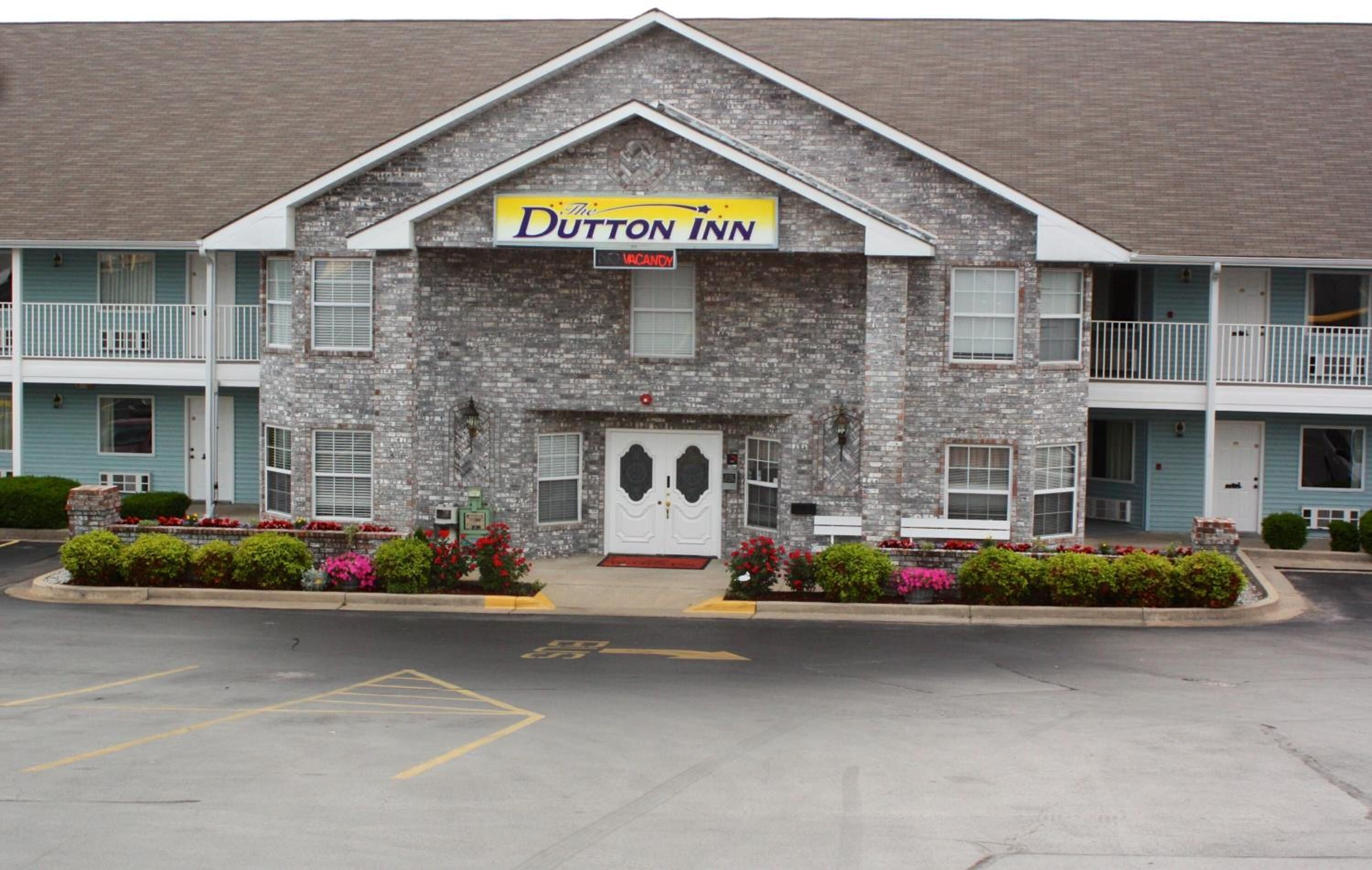 A two-story Dutton Inn with a brick facade, a central entrance, and a balcony on the upper floor.