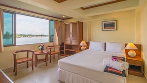 Habitación de hotel con una cama grande, dos mesitas de noche, un escritorio con sillas, vista al mar y un cuadro en la pared.