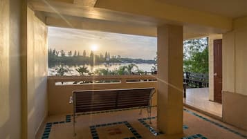 A balcony with a bench, a view of a body of water, and a distant cityscape.