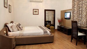 A bedroom with a bed, a TV, a desk, and a chair. - 66 Residency - A Boutique Hotel (Jaipur)