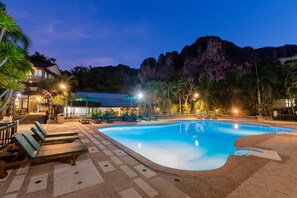 A swimming pool with lounge chairs, a building with a covered patio, and a mountainous backdrop. - Green View Village Resort (Krabi)