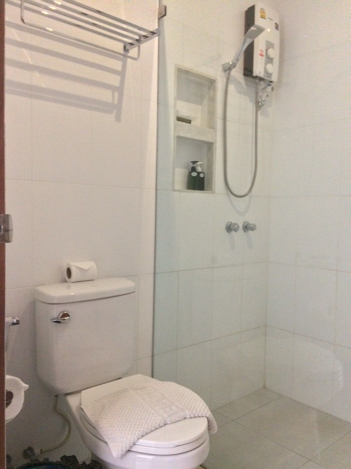 Un baño con inodoro, ducha y toallero.