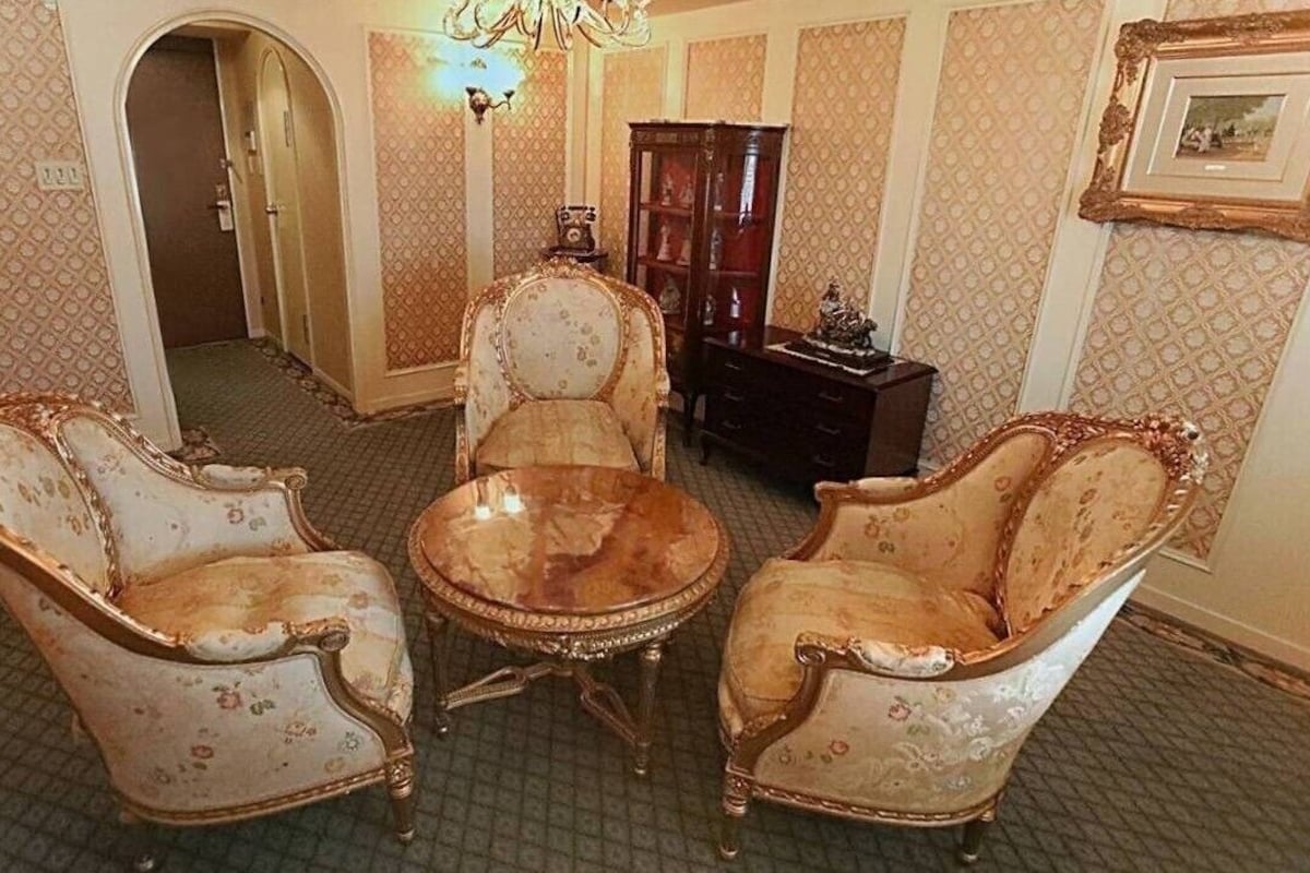 A room with ornate furniture, a chandelier, and a patterned wallpaper.