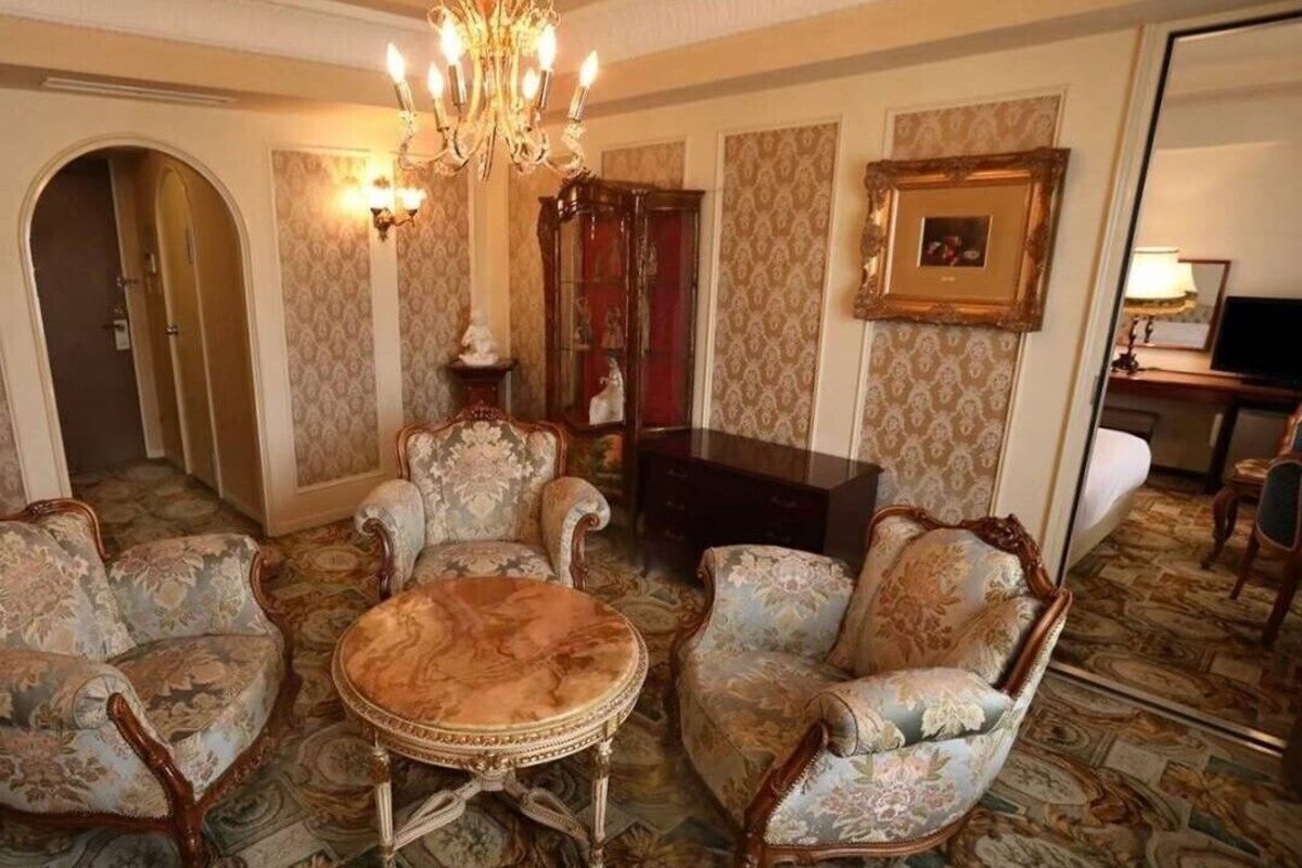 A room with ornate furniture, a chandelier, and patterned wallpaper.