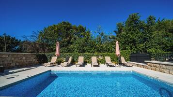 Alberca al aire libre, sombrillas en la alberca y camastros