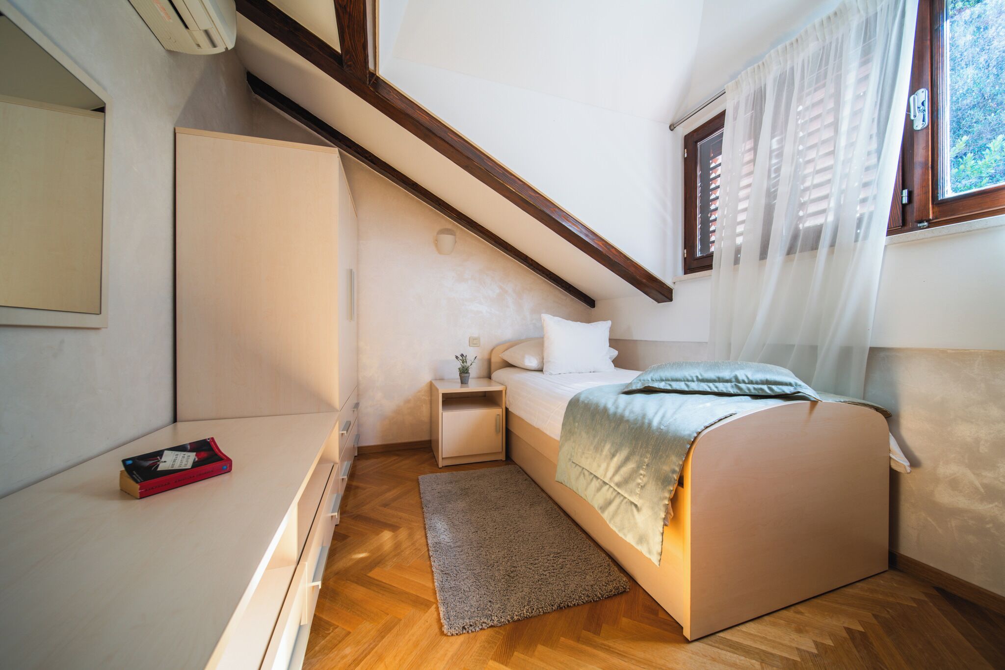 Une chambre à coucher avec un lit, une table de chevet et une petite commode.