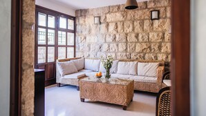 Una sala de estar acogedora con pared de piedra, un conjunto de sofás, una mesa de centro y una lámpara colgante.