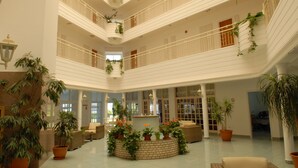 A spacious atrium with multiple floors, large windows, and potted plants. - Maistrali Hotel Apts (Protaras)
