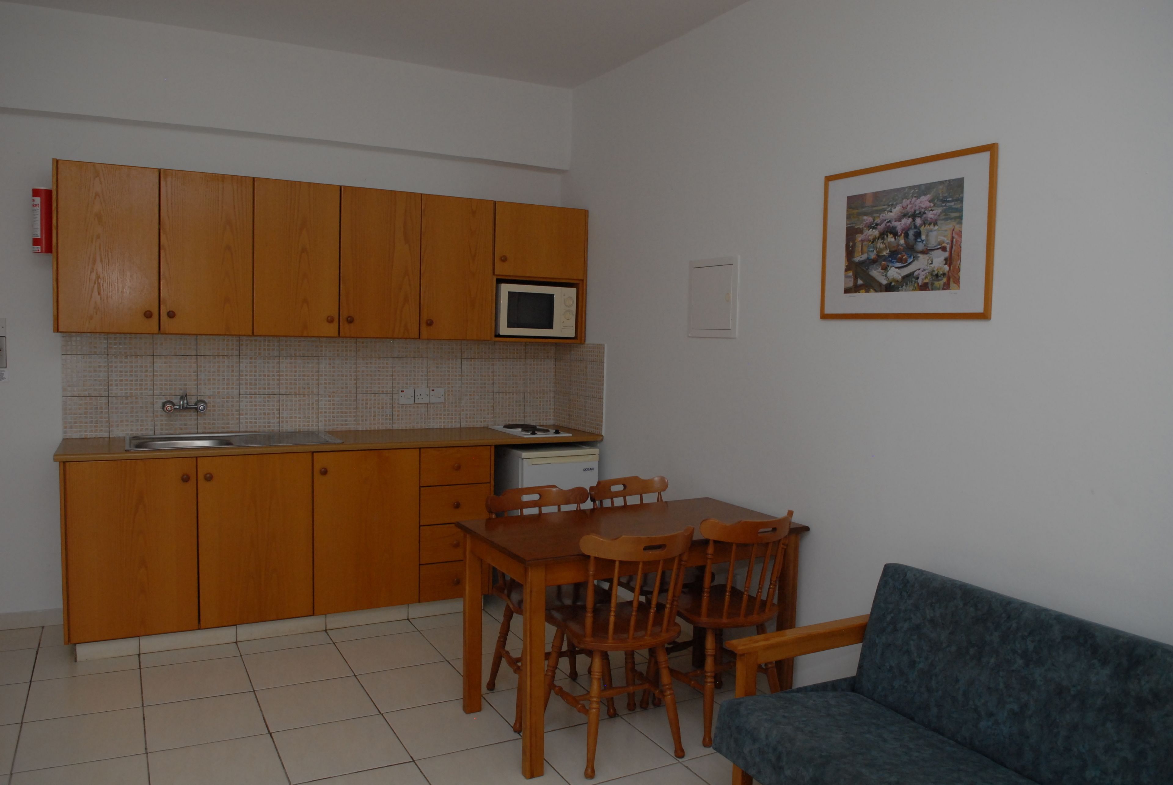 A compact kitchen with wooden cabinets, a microwave, and a dining table with chairs.