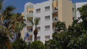 A multi-story hotel with balconies, surrounded by palm trees and other greenery. - Maistrali Hotel Apts (Protaras)