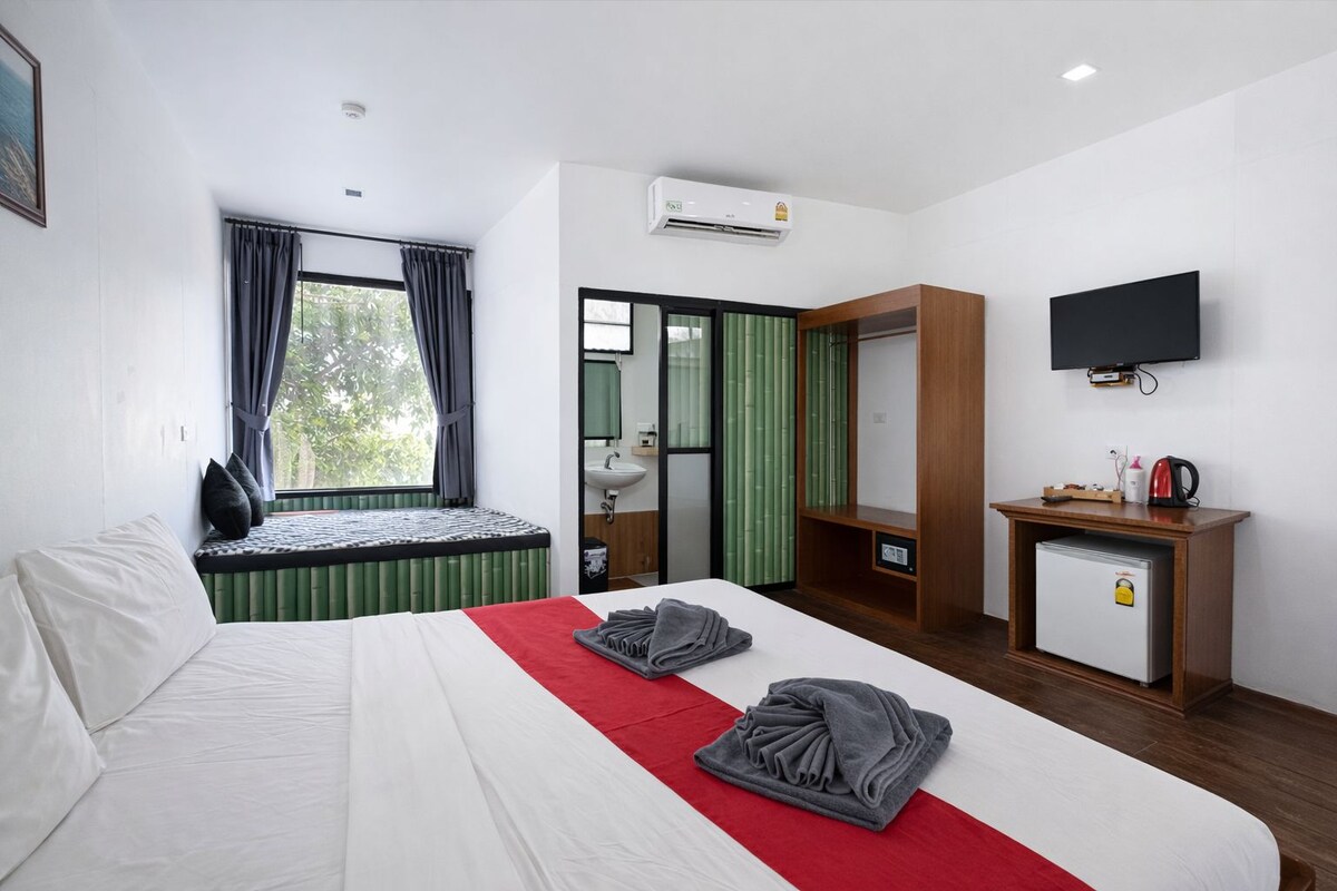 Ein Hotelzimmer mit Bett, Schreibtisch, Fernseher und einem Fenster mit Vorhängen.