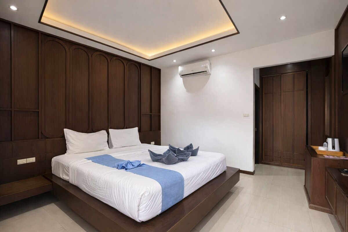 Ein modernes Hotelzimmer mit einem großen Bett, Holzvertäfelung, einer Klimaanlage und einem Schreibtisch mit Stuhl.