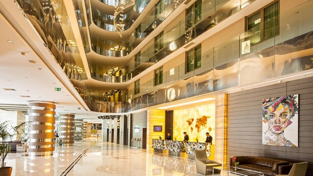 Un atrium à plusieurs niveaux, doté de revêtements de sol réfléchissants, de rampes en verre et d’un espace central ouvert.