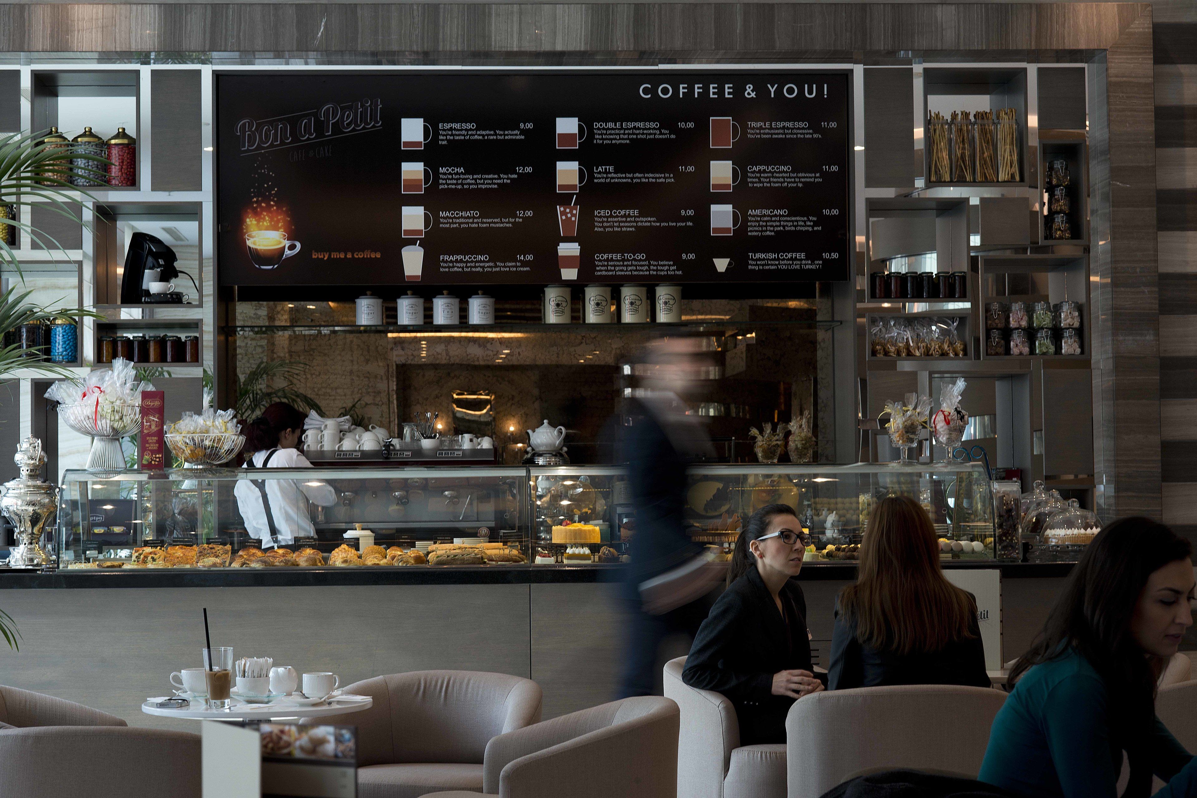 Una cafetería con un panel de menú que muestra diferentes opciones de café.