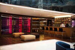 A modern bar area with a bartender, bar stools, and shelves of bottles. - Radisson Blu Hotel, Istanbul Sisli (Istanbul)