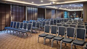 A conference room with rows of chairs, a projector, and a stage.