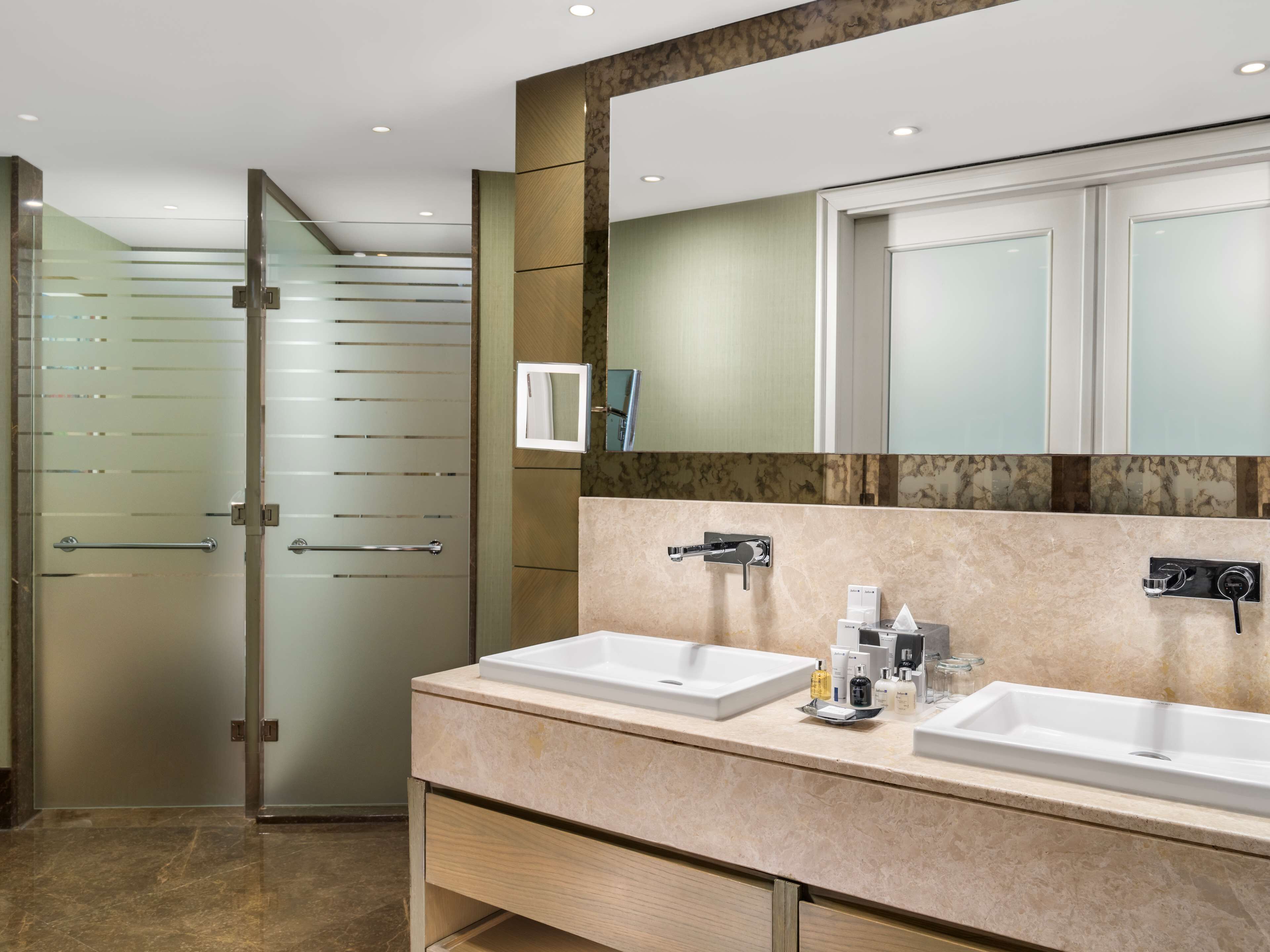 A modern bathroom with two sinks, a large mirror, and a glass shower enclosure.