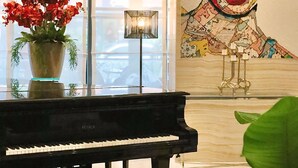 Un piano, une plante en pot et un grand tableau abstrait dans une pièce avec une fenêtre.
