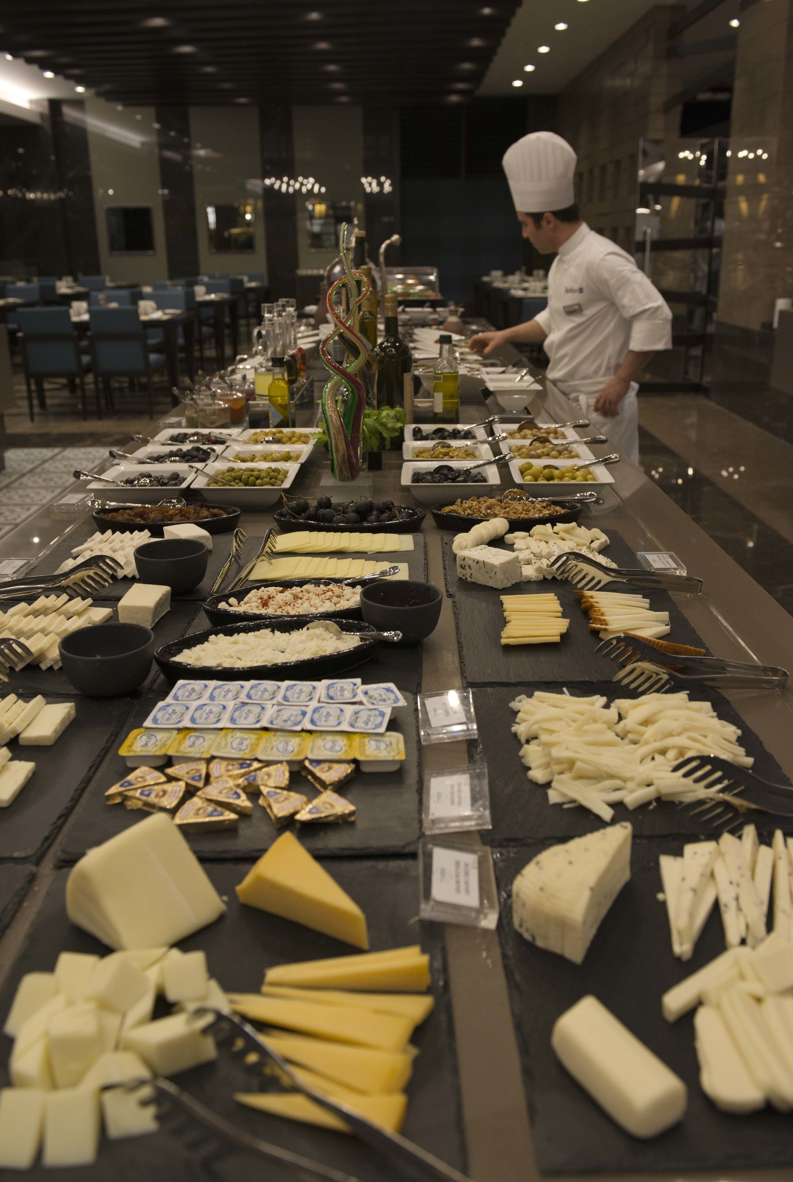 Una mesa de buffet con varios quesos, aceitunas y otras comidas.