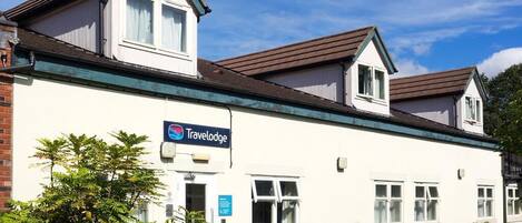 Un hôtel Travelodge avec une façade blanche, un toit vert et une enseigne.